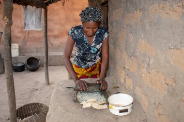 Opialu, Benue State - 6 Mart 2021: Afrikalı Kadın Çamur Evi 'nin yakınındaki Kavun ezmek için Yerel Öğütme Değirmeni' ni (Stone) kullanıyor.