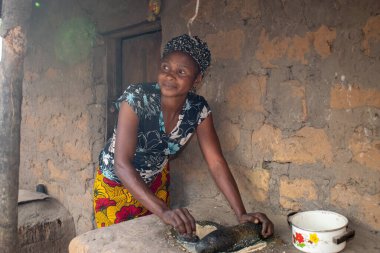 Opialu, Benue State - 6 Mart 2021: Afrikalı Kadın Çamur Evi 'nin yakınındaki Kavun ezmek için Yerel Öğütme Değirmeni' ni (Stone) kullanıyor.