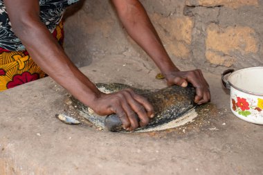 Opialu, Benue State - 6 Mart 2021: Afrikalı Kadın Çamur Evi 'nin yakınındaki Kavun ezmek için Yerel Öğütme Değirmeni' ni (Stone) kullanıyor.