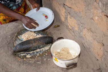 Opialu, Benue State - 6 Mart 2021: Afrikalı Kadın Çamur Evi 'nin yakınındaki Kavun ezmek için Yerel Öğütme Değirmeni' ni (Stone) kullanıyor.
