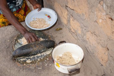 Opialu, Benue State - 6 Mart 2021: Afrikalı Kadın Çamur Evi 'nin yakınındaki Kavun ezmek için Yerel Öğütme Değirmeni' ni (Stone) kullanıyor.