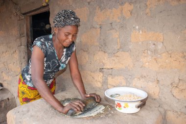 Opialu, Benue State - 6 Mart 2021: Afrikalı Kadın Çamur Evi 'nin yakınındaki Kavun ezmek için Yerel Öğütme Değirmeni' ni (Stone) kullanıyor.