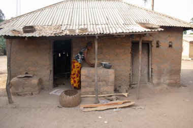 Opialu, Benue State - 6 Mart 2021: Afrikalı Kadın Çamur Evi 'nin yakınındaki Kavun ezmek için Yerel Öğütme Değirmeni' ni (Stone) kullanıyor.