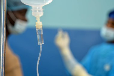 Abuja Nigeria - July 7, 2023: African Plastic Surgeons in a soft focus blue background. Normal Saline IV infusion prepared for surgery.