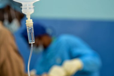 Abuja Nigeria - July 7, 2023: African Plastic Surgeons in a soft focus blue background. Normal Saline IV infusion prepared for surgery.