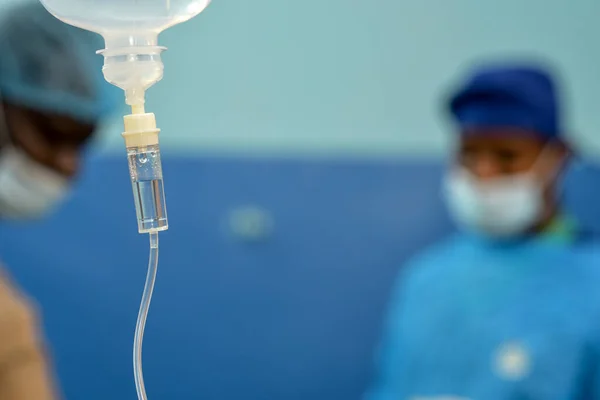 Abuja Nigeria - July 7, 2023: African Plastic Surgeons in a soft focus blue background. Normal Saline IV infusion prepared for surgery.
