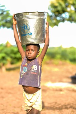 Talata, Plateau State - June, 2023: African Boy carrying Water from a Newly Built Indian Hand Pump. Community Members Fetching Water for Domestic Use. clipart