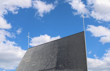 Mavi gökyüzünün altındaki bir kilisenin önündeki haçın alçak açılı görüntüsü.