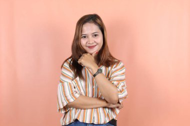 Güzel Asyalı kadın kendini mutlu ve rahat hissediyor. Şeftali arkaplanlı.