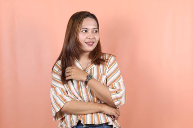 Güzel Asyalı kadın kendini mutlu ve rahat hissediyor. Şeftali arkaplanlı.