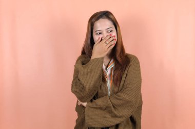 Güzel Asyalı kadın kendini mutlu ve rahat hissediyor. Şeftali arkaplanlı.