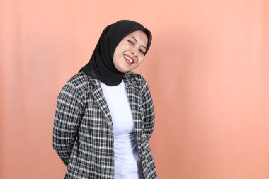 Güzel Müslüman Asyalı kadın, mutlu ve rahat, şeftali arkaplanlı.