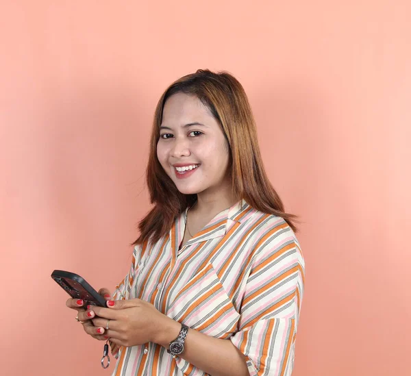 Счастливая Азиатская Женщина Держит Смартфон Персиковом Фоне — стоковое фото