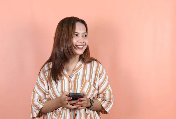 Ευτυχισμένη Όμορφη Ασιατική Γυναίκα Κρατώντας Smartphone Φόντο Ροδακινί — Φωτογραφία Αρχείου