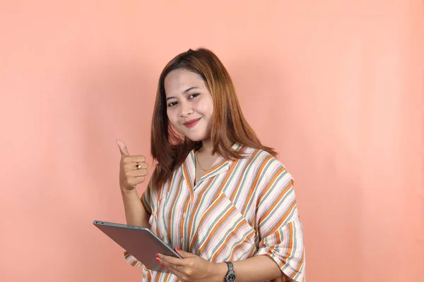 若い美しいアジアの女性 会社の労働者 親指を放棄し デジタルタブレットを保持 桃の背景に — ストック写真