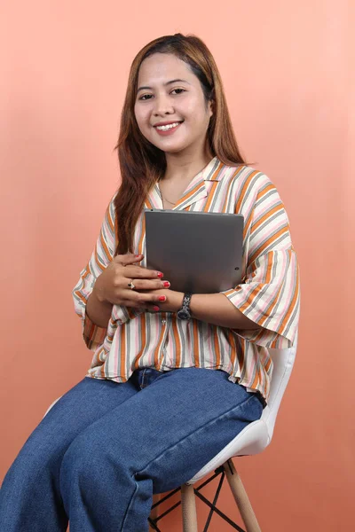 若い美しいアジアの女性 会社の労働者 笑顔と桃の背景と白い椅子に座ってデジタルタブレットを保持 — ストック写真