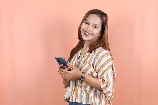 Glücklich Schöne Asiatin Hält Smartphone Auf Pfirsichhintergrund — Stockfoto