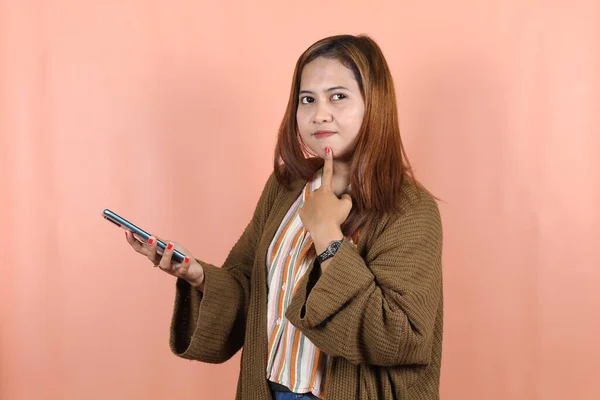 スマートフォンを持って桃を背景に考える美しいアジアの女性 — ストック写真