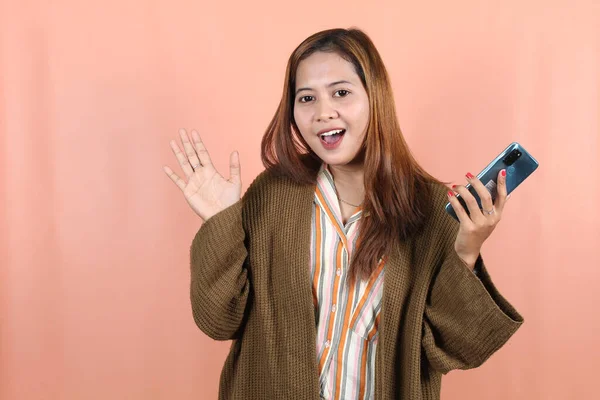 Šťastná Krásná Asijská Žena Drží Smartphone Pocit Šoku Broskvovém Pozadí — Stock fotografie