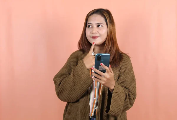 Mooie Aziatische Vrouw Holding Smartphone Denken Perzik Achtergrond — Stockfoto