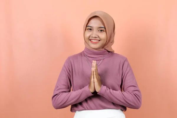 ヒジャーブを着た若いアジア系イスラム女性が顔に大きな笑顔で挨拶する 桃の背景にあるインドネシア人女性 イード挨拶 イードアルフィルト イードアルフィルト — ストック写真