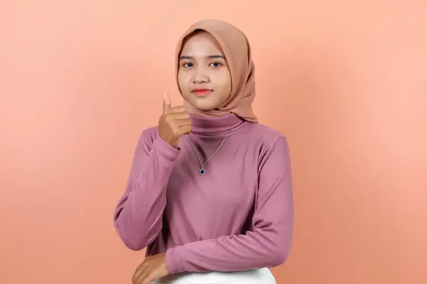 漂亮的年轻的亚洲穆斯林妇女戴着紫色毛衣和棕色面纱 竖起大拇指表示认可 — 图库照片