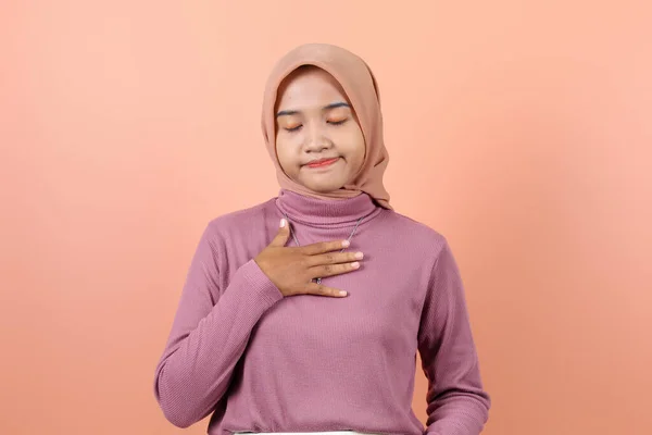 美しい若いアジアのイスラム教徒の女性は 紫色の水を身に着けている患者が言う彼女の胸を持っています — ストック写真