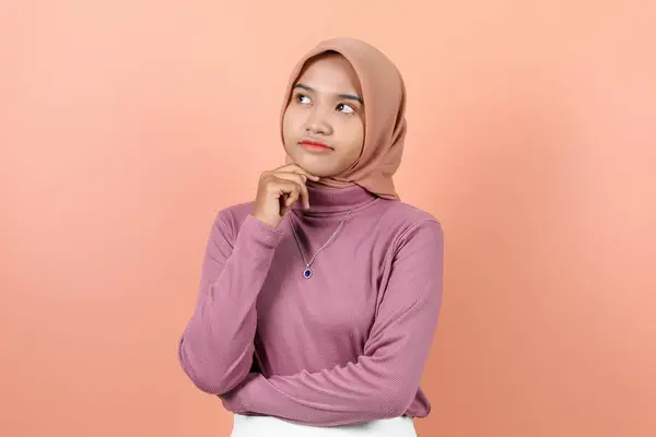 美丽的亚洲年轻的穆斯林女子 眼睛抬起 手放在下巴下 身穿紫色毛衣 思维敏捷 — 图库照片