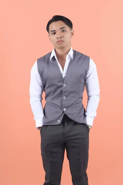 ハンサムで笑顔のアジアの若い男性は 正式なスーツベストを着用して 自信を持ってポケットに両手でカメラを見ます — ストック写真