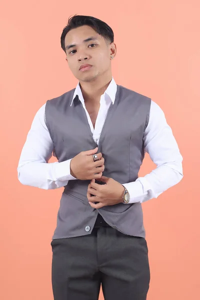 スーツのベストを着ているハンサムな若いアジアのビジネスマンは自信を持ってスタイリッシュにピーチの背景に自信を持って彼のベストをボタン化 — ストック写真