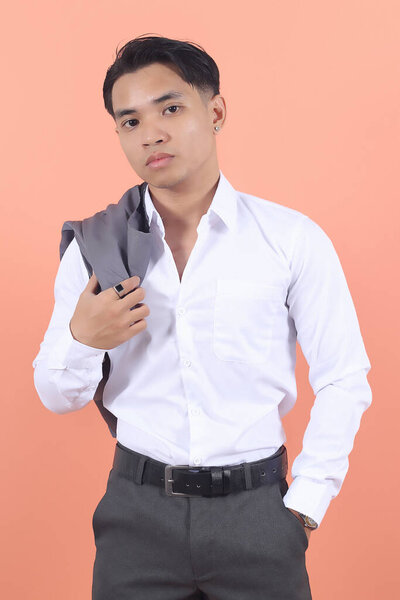 A young Asian businessman in a white shirt hangs his vest over his shoulder, looking confidently into the camera.