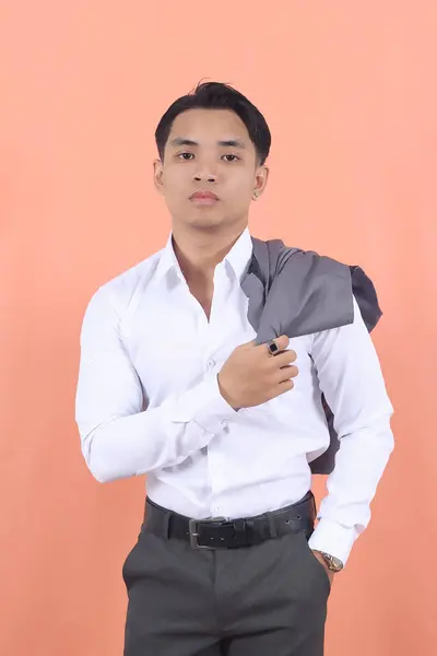 白いシャツを着た若いアジアのビジネスマンは 自信を持ってカメラに目を向け 肩にベストを掛けます — ストック写真