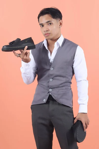 잘생긴 아시아인 남자가 형식적인 정장을 가지고있는 공식적인 판타지 신발을 보여줍니다 — 스톡 사진