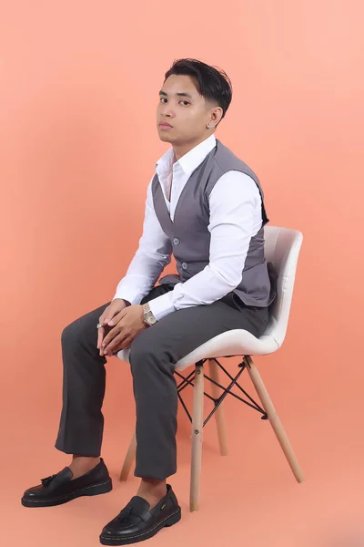 Młody Azjatycki Biznesmen Garniturze Kamizelka Gapi Się Aparat Siedzi Białym — Zdjęcie stockowe