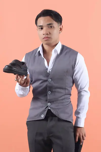잘생긴 아시아인 남자가 형식적인 정장을 가지고있는 공식적인 판타지 신발을 보여줍니다 — 스톡 사진