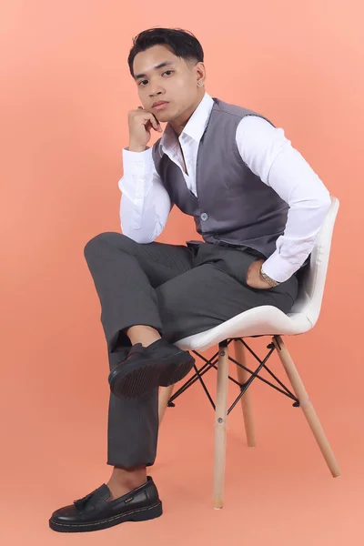 スーツのベストを着た若いアジアの実業家は 自信を持って足で白い椅子に座っているカメラにスターを着けます — ストック写真