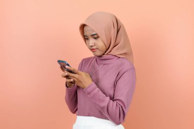 Suratı asık, güzel bir Asyalı kadın elinde telefon tutuyor.