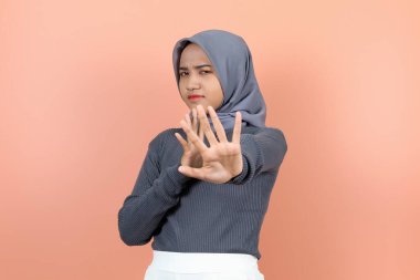 Güzel, genç bir Asyalı kadın bir eli açık, bir eli açık, yüzü asık bir şekilde bir şeyi engelliyor..