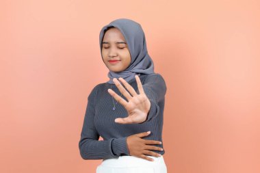 Güzel, genç Asyalı bir kadın bir eliyle karnını tutuyor diğer eliyse gözleri kapalıyken bir şey tutuyor.