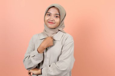 Güzel genç Asyalı kadın da diğer elini göğsünde tutuyor ve diğeri de gülümserken çapraz duruyor.