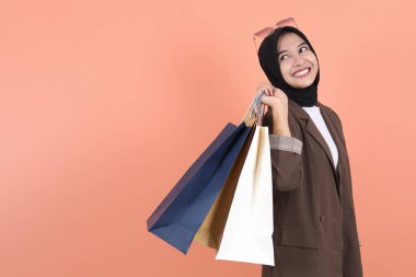 Güzel, genç Müslüman bir kadın alışveriş çantasıyla mutlu mesut geziyor.