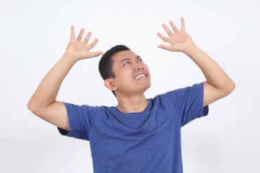 Şaşırmış Asyalı adam beyaz arka planda reklam için ellerini kaldırarak yukarı bakıyor..