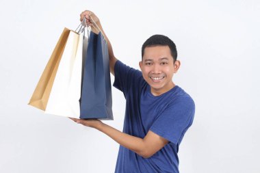 Mutlu Asyalı genç alışverişçi, izole edilmiş beyaz alışveriş torbaları taşıyor.