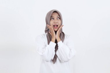 Güzel Asyalı Müslüman kadın çenesini iki eli açık, yüzü yukarıya dönük ve ağzı açık bir şekilde dişlerini gösteriyor.