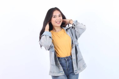 Neşeli Asyalı kadın, özgüvenli bir şekilde gülümseyen, elleri saçında, mavi ceketli ve sarı tişörtlü, izole edilmiş beyaz arka planda kameraya bakan.