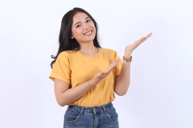 Sarı tişört giyen mutlu genç Asyalı kadın beyaz arka planda izole edilmiş ürünler için açık avuç içi fotokopi alanı sunuyor ya da gösteriyor