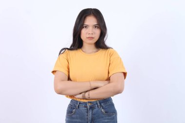 Güzellik, insanlar duygular ve duygu yüz ifadesi kavramı. Kasvetli, çekingen, çekingen, utangaç, dargın, göğsünde çapraz kollar, üzgün, şikayetçi, beyaz arka planda oturan Asyalı kız.