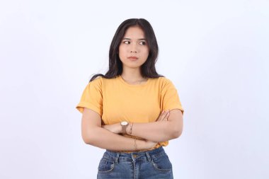 Güzellik, insanlar duygular ve duygu yüz ifadesi kavramı. Kasvetli, çekingen, çekingen, utangaç, dargın, göğsünde çapraz kollar, üzgün, şikayetçi, beyaz arka planda oturan Asyalı kız.