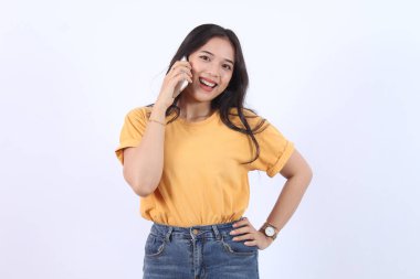 Dost canlısı gülümseyen Asyalı kadın telefonda konuşuyor, nöbetçi kız, akıllı telefonu tutuyor ve gülüyor, konuşuyor, beyaz arka planda duruyor.