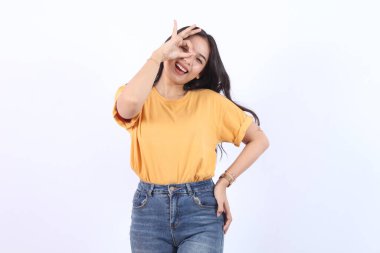 Genç ve güzel Asyalı bir kadının portresi gülümsüyor ve elinde beyaz arka planda izole edilmiş iyi bir işaret var.